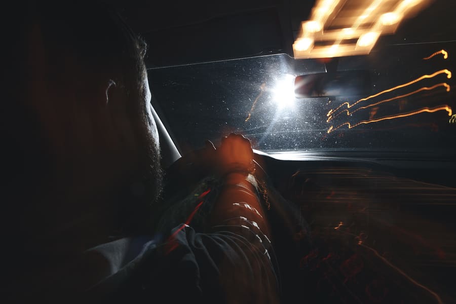 a man driving a car at night with lights on